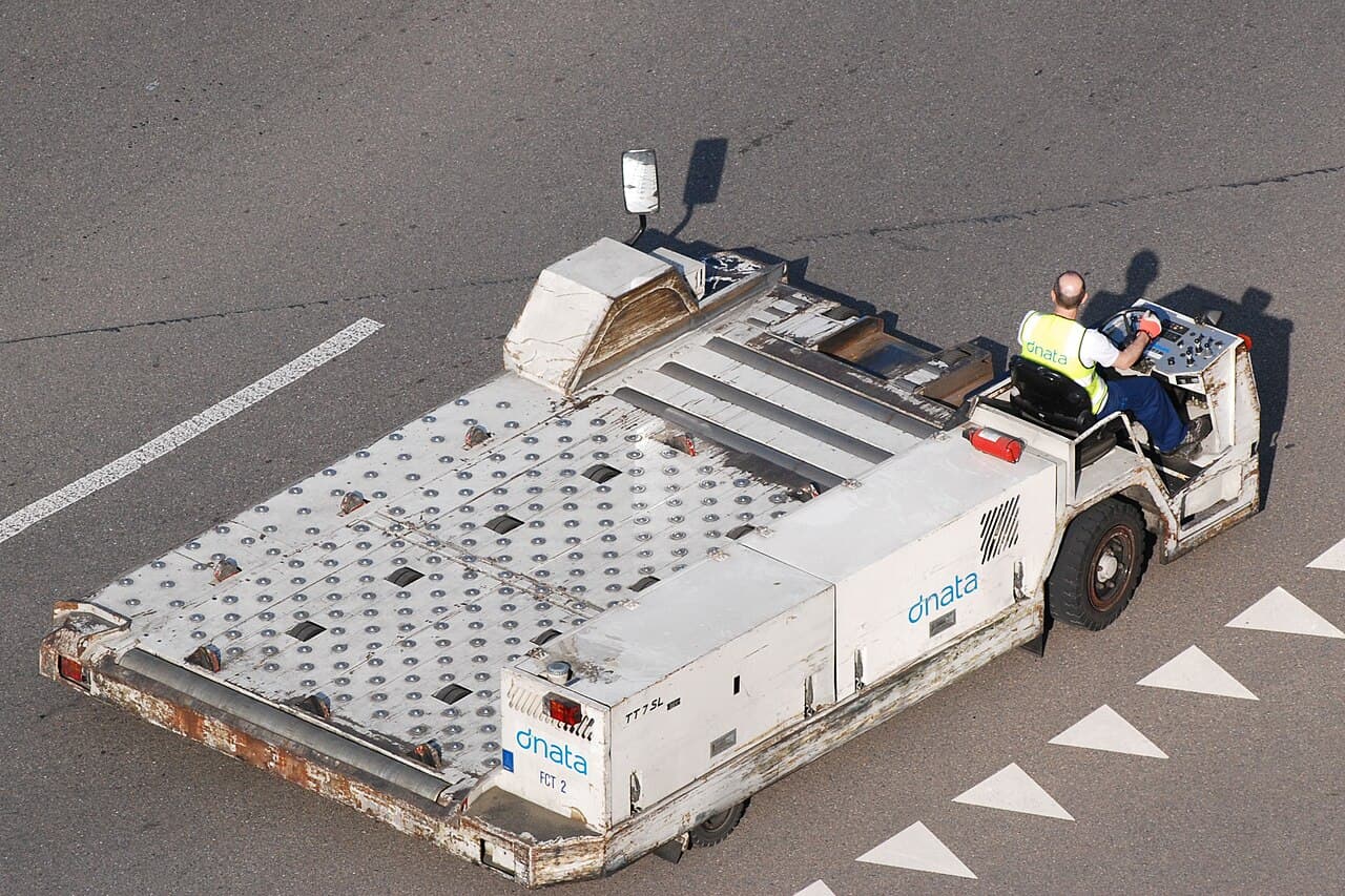 Ground crew driving an aircraft cargo loader